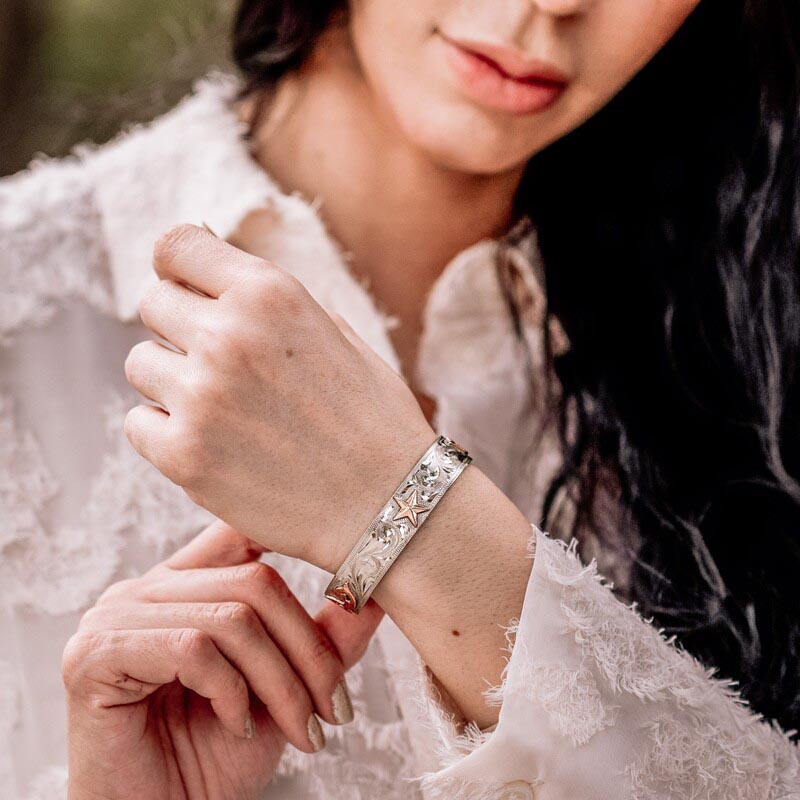 Woman wearing a silver western cuff bracelt with custom golden figure